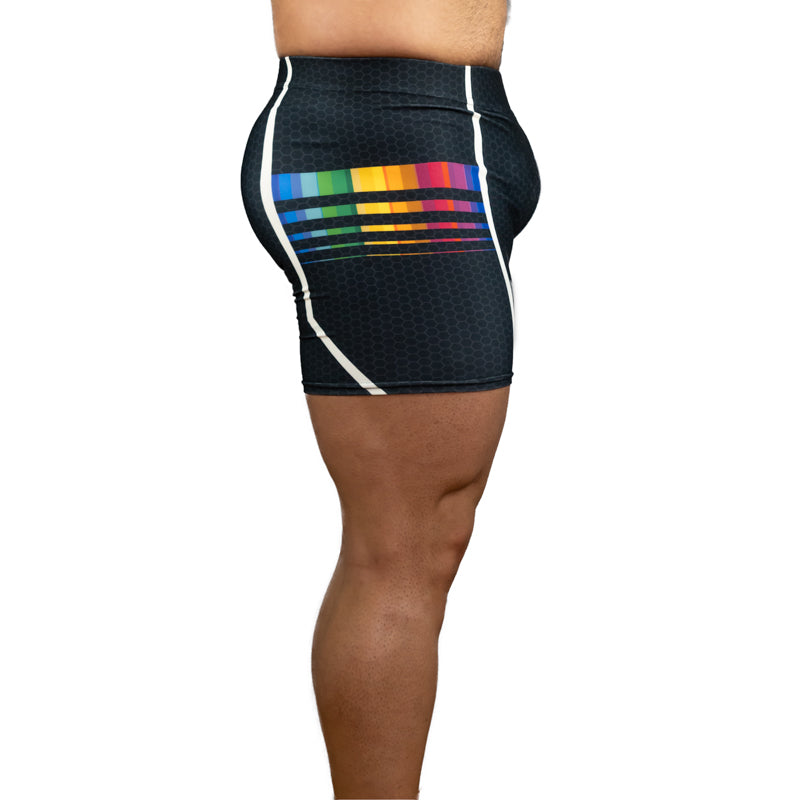 Side view of a person wearing fitted athletic shorts in black with white side panels and a rainbow stripe graphic on the back side, against a plain white background.